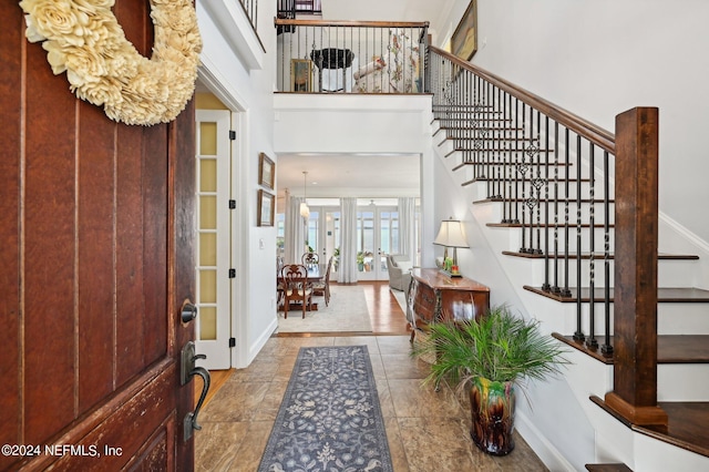 foyer entrance with french doors, a high ceiling, stairway, and baseboards