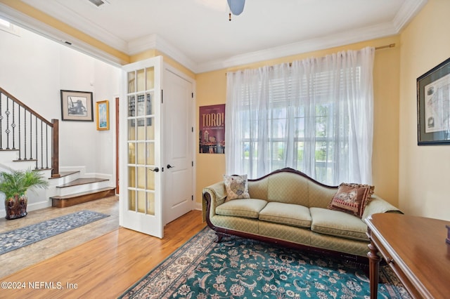 living area with stairs, crown molding, baseboards, and wood finished floors