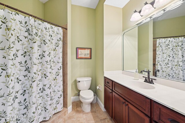 full bathroom featuring toilet, a shower with shower curtain, vanity, baseboards, and tile patterned floors