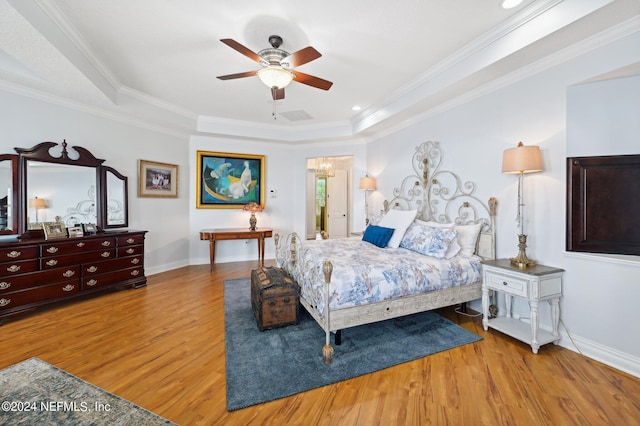 bedroom with ornamental molding, light wood finished floors, a raised ceiling, and baseboards