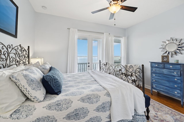 bedroom with baseboards, ceiling fan, wood finished floors, a water view, and access to outside