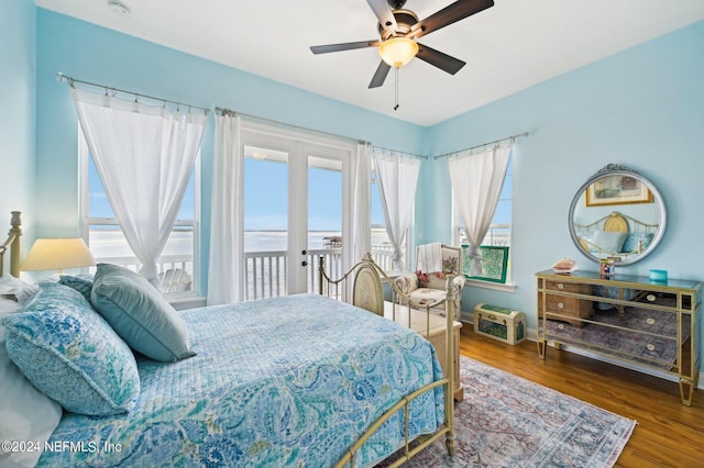 bedroom with baseboards, dark wood-style floors, ceiling fan, a water view, and access to outside