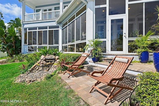 exterior space featuring a balcony, a sunroom, and a patio