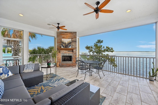 exterior space with a ceiling fan, an outdoor stone fireplace, and a water view