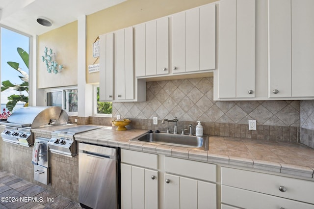 kitchen with tile countertops, a sink, white cabinetry, and refrigerator