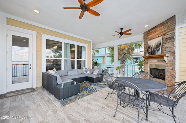 view of patio featuring ceiling fan, an outdoor living space with a fireplace, and outdoor dining area