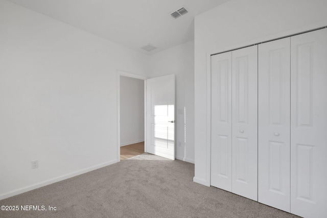 unfurnished bedroom featuring light colored carpet and a closet