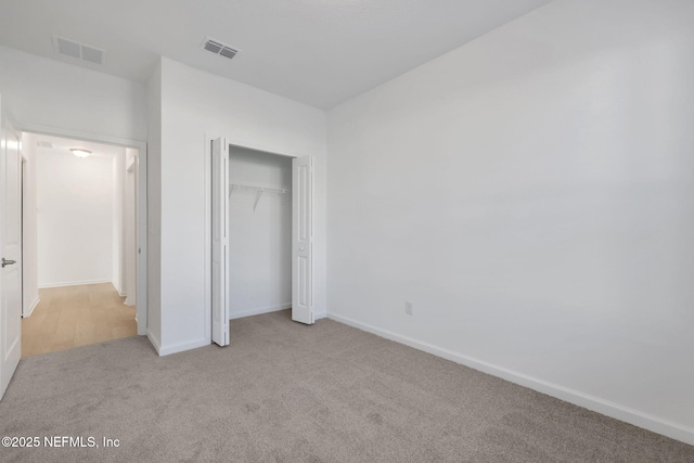 unfurnished bedroom featuring light colored carpet and a closet