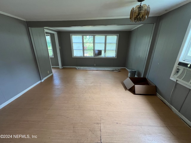 empty room with an inviting chandelier, cooling unit, crown molding, and hardwood / wood-style floors