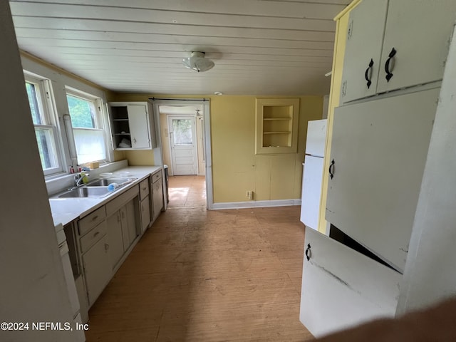 kitchen with a sink, light countertops, light wood-type flooring, freestanding refrigerator, and open shelves