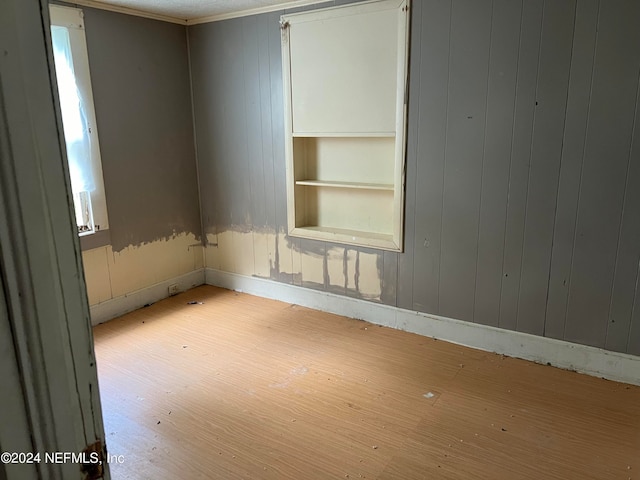 empty room with built in shelves and light hardwood / wood-style floors