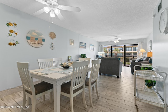 dining space featuring a ceiling fan, wood tiled floor, and a textured ceiling