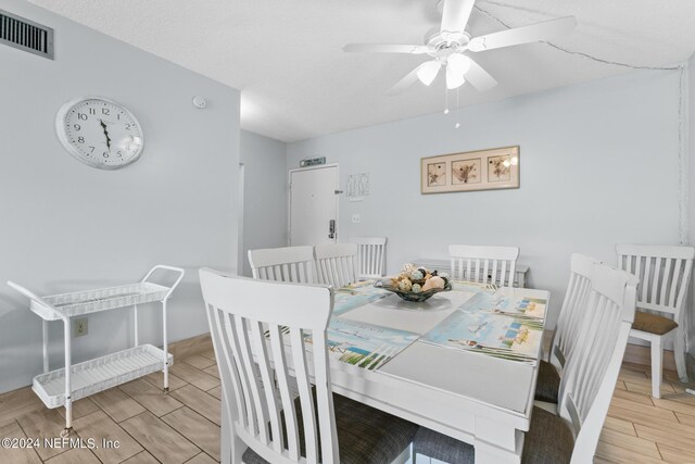 dining room with wood finish floors, visible vents, and ceiling fan