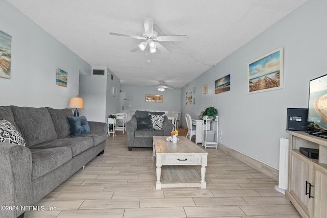 living room with wood tiled floor, visible vents, and ceiling fan