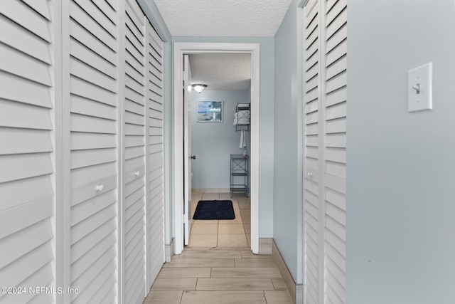 hallway with wood tiled floor, baseboards, and a textured ceiling