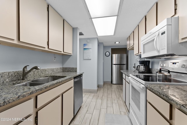 kitchen featuring stone counters, wood finish floors, appliances with stainless steel finishes, a sink, and baseboards