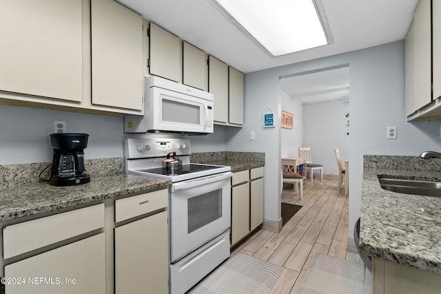 kitchen with light stone counters, wood tiled floor, white appliances, and a sink