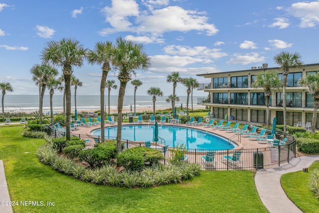 pool featuring a water view, a lawn, and a patio