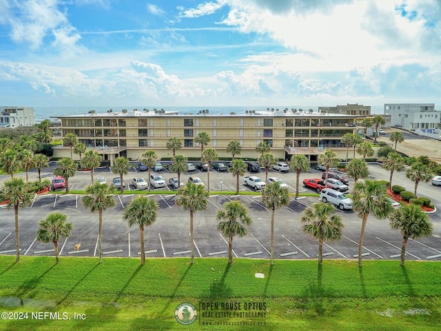 view of building exterior with uncovered parking and a water view