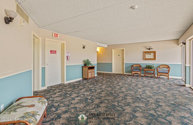 sitting room with carpet flooring, a textured ceiling, and baseboards