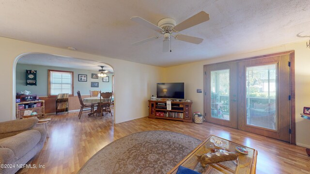 living room with a textured ceiling, light wood-type flooring, ceiling fan, and a healthy amount of sunlight