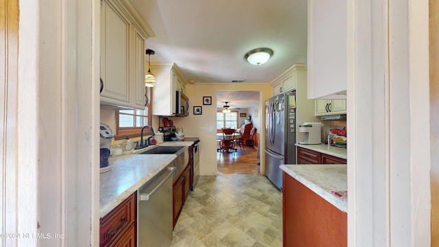 kitchen with cream cabinets, light wood-type flooring, stainless steel appliances, and pendant lighting