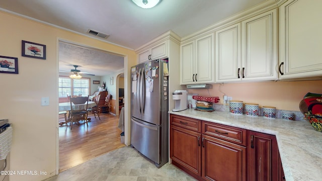 kitchen featuring ceiling fan, cream cabinets, light hardwood / wood-style floors, and stainless steel refrigerator