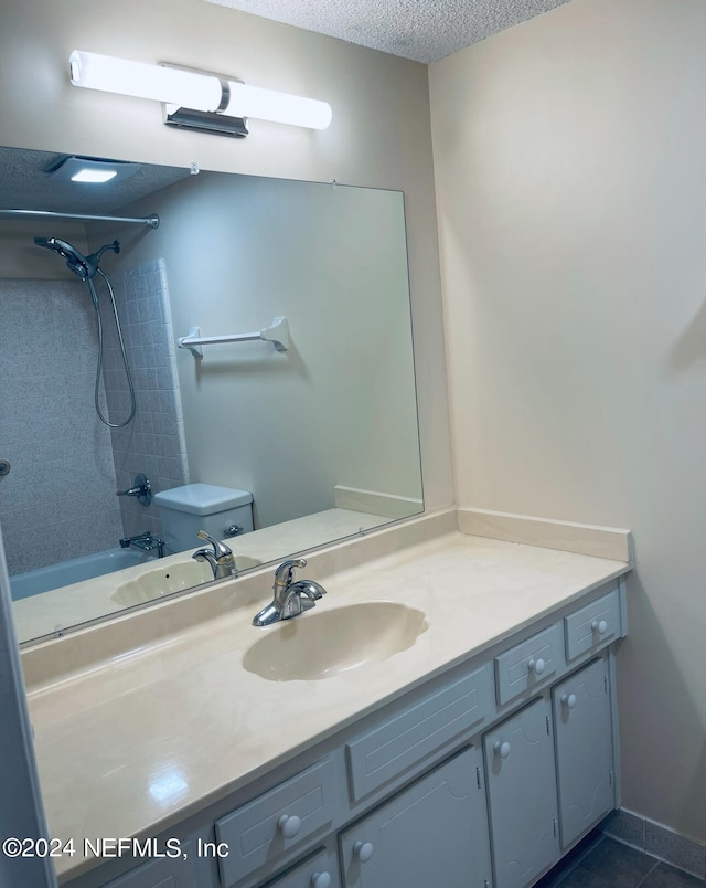 full bathroom featuring a textured ceiling, vanity, tiled shower / bath, and toilet