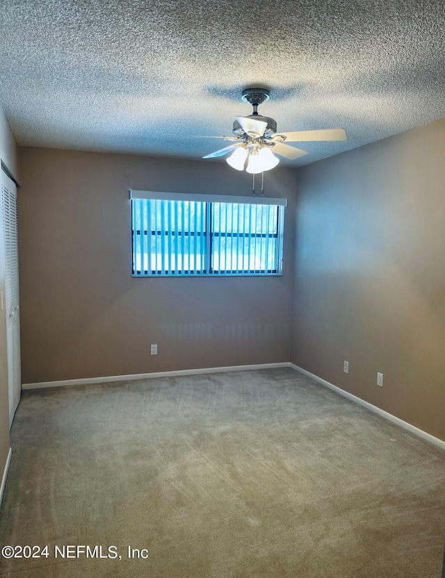 spare room with a textured ceiling, ceiling fan, and carpet flooring