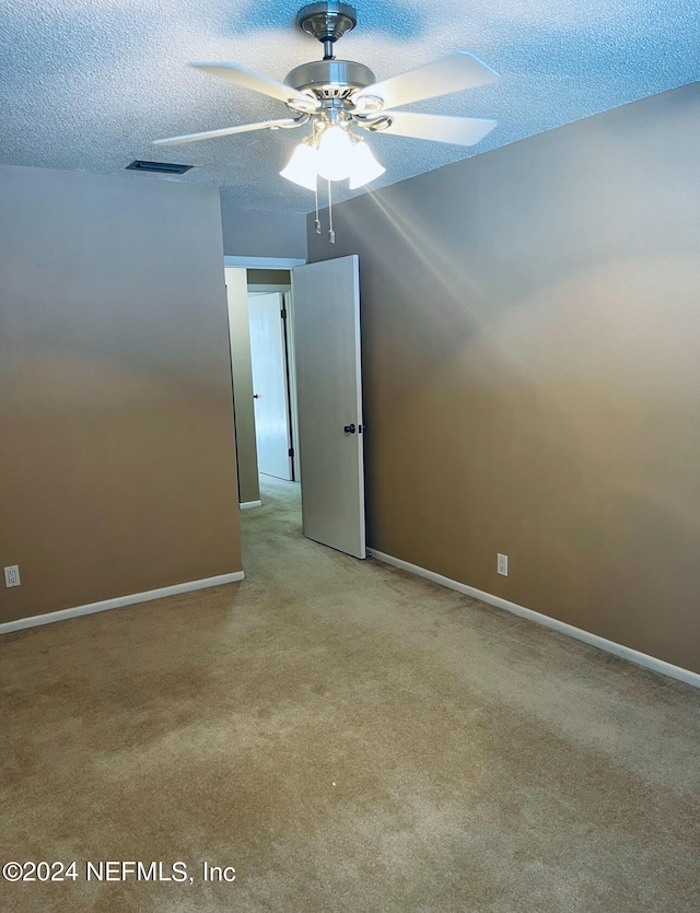 spare room with light carpet, ceiling fan, and a textured ceiling