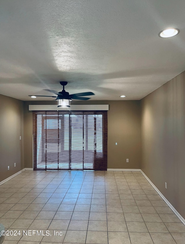 tiled spare room with a textured ceiling and ceiling fan