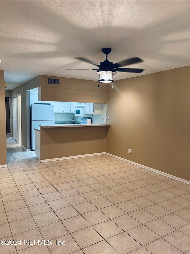 empty room featuring light tile patterned flooring, a textured ceiling, and ceiling fan