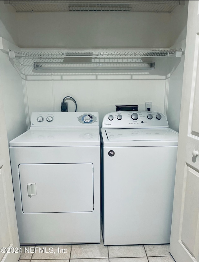 clothes washing area with light tile patterned flooring and washer and dryer