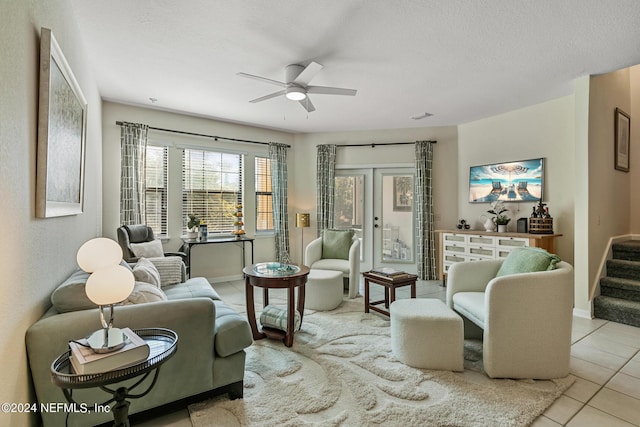 living area with a textured ceiling, a ceiling fan, stairs, french doors, and tile patterned floors