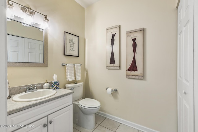 bathroom with baseboards, toilet, tile patterned flooring, vanity, and a closet