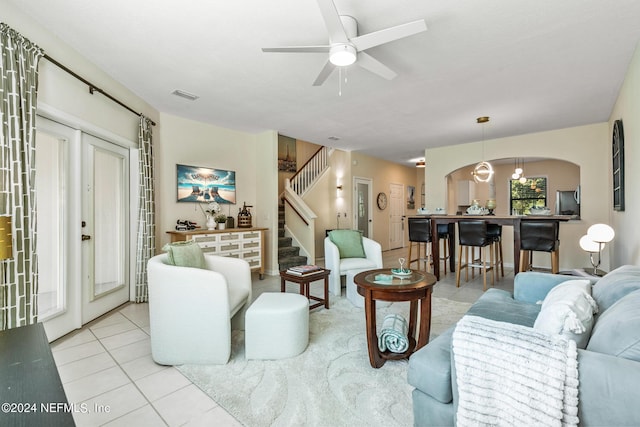 living room featuring visible vents, arched walkways, a ceiling fan, stairway, and tile patterned floors