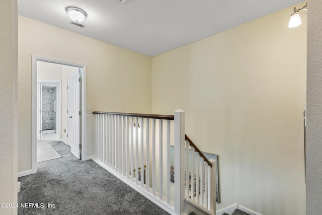 hallway with baseboards, visible vents, carpet flooring, and an upstairs landing