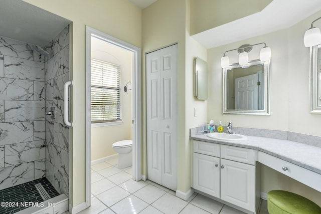 bathroom featuring vanity, tile patterned floors, toilet, and a tile shower