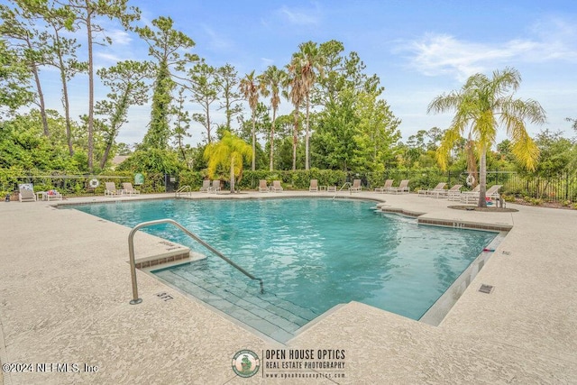 community pool with a patio and fence