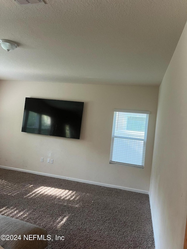 interior space with dark carpet, a textured ceiling, and baseboards