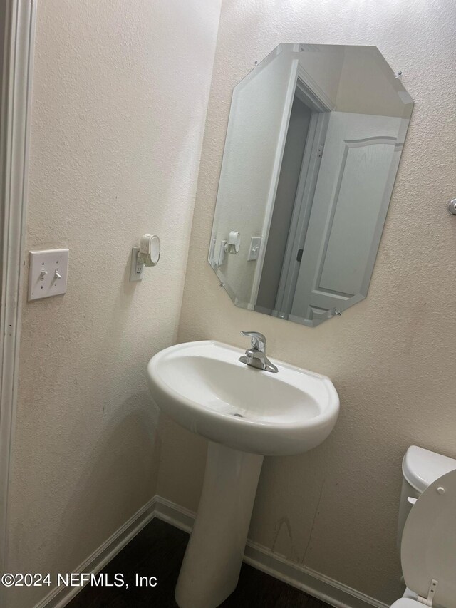 half bath with toilet, baseboards, and a textured wall