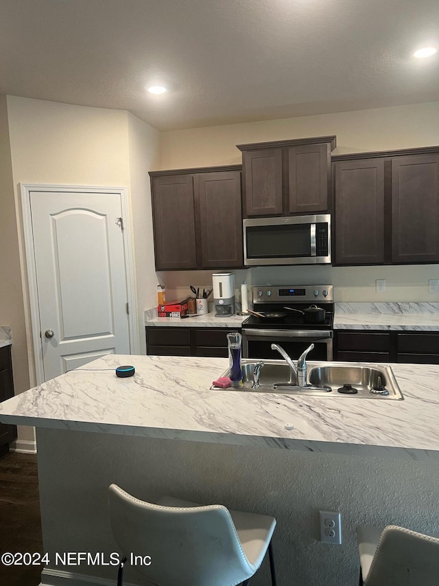 kitchen featuring appliances with stainless steel finishes, light countertops, dark brown cabinets, and a breakfast bar area