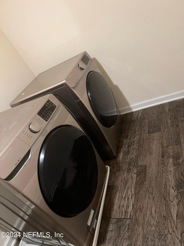 clothes washing area featuring laundry area, baseboards, washer and clothes dryer, and wood finished floors