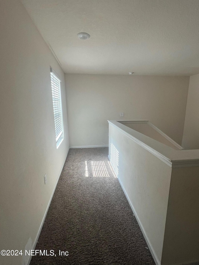 corridor featuring an upstairs landing, carpet flooring, and baseboards