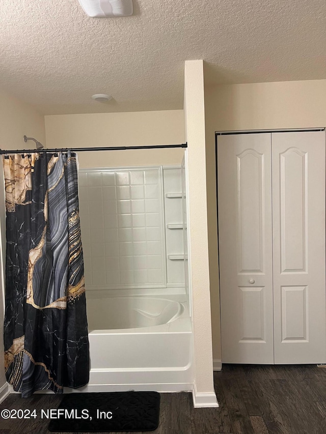 full bathroom featuring a textured ceiling, a closet, wood finished floors, and shower / tub combo with curtain