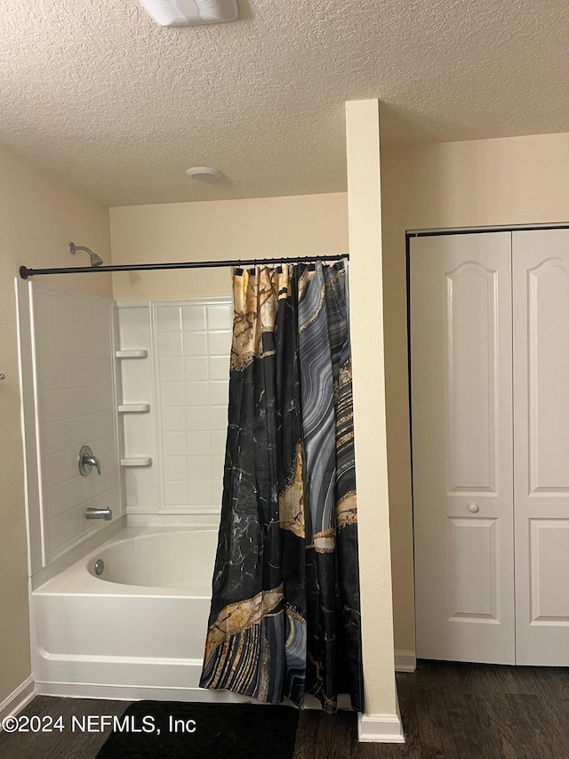 bathroom featuring a textured ceiling, baseboards, shower / tub combo with curtain, and wood finished floors