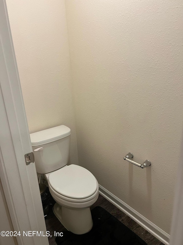 bathroom with toilet, baseboards, and wood finished floors