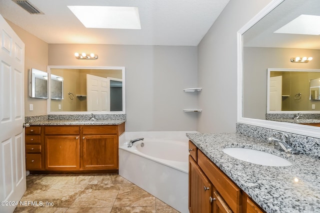 bathroom with a tub to relax in, a skylight, and vanity