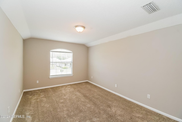 carpeted spare room with vaulted ceiling