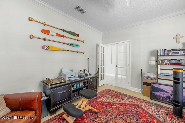 interior space with ornamental molding, french doors, a textured ceiling, and light wood-type flooring